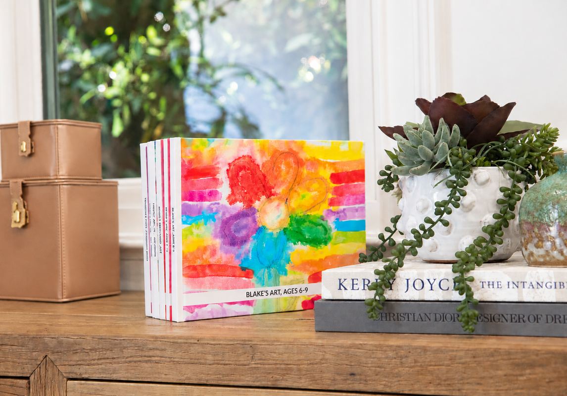 A finished Kids Art Book standing on a shelf beside a plant