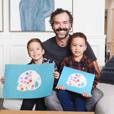 A dad and his two kids holding up their Kids Art Books